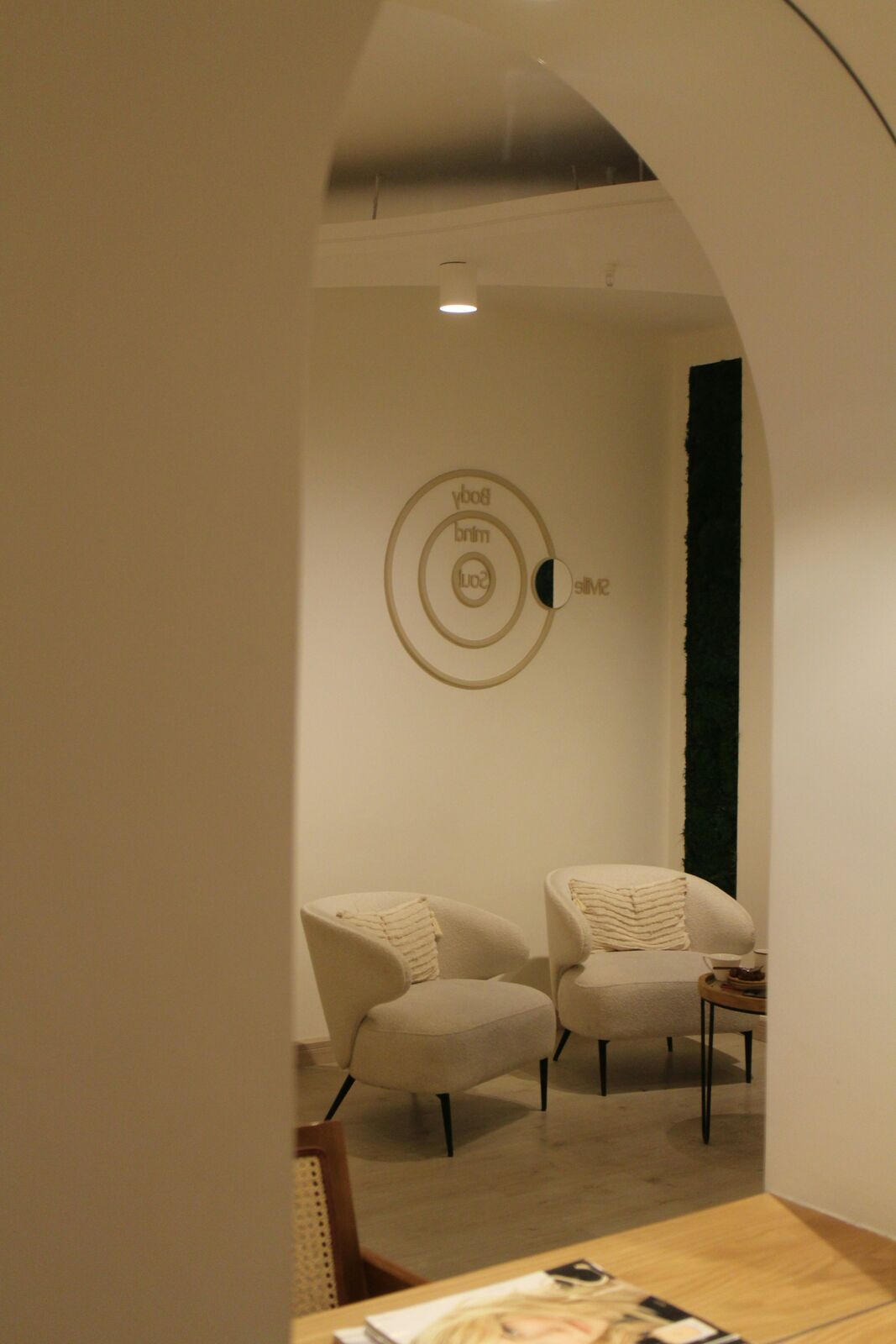 A view through an arch into a calm lounge with cream armchairs