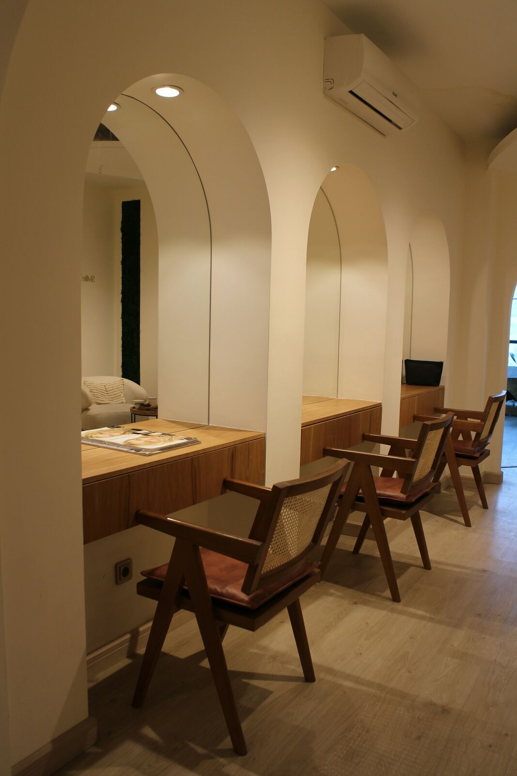 Plaster arches over a row of wooden chairs in warm light