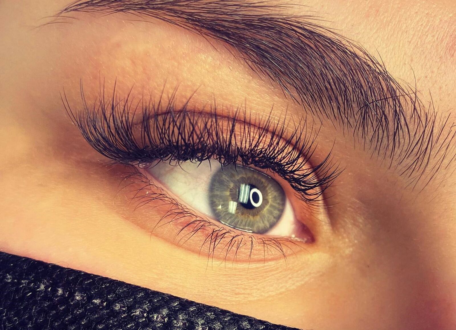 Close-up of an eye with full, lifted lashes and a groomed brow