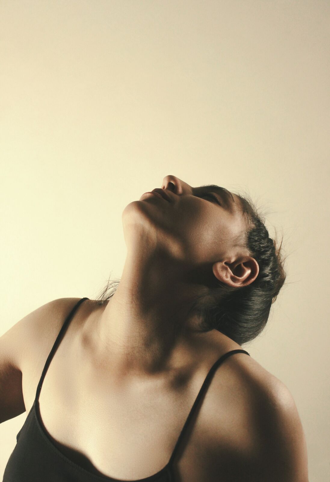 A woman with her head tilted back, eyes closed, in soft warm light