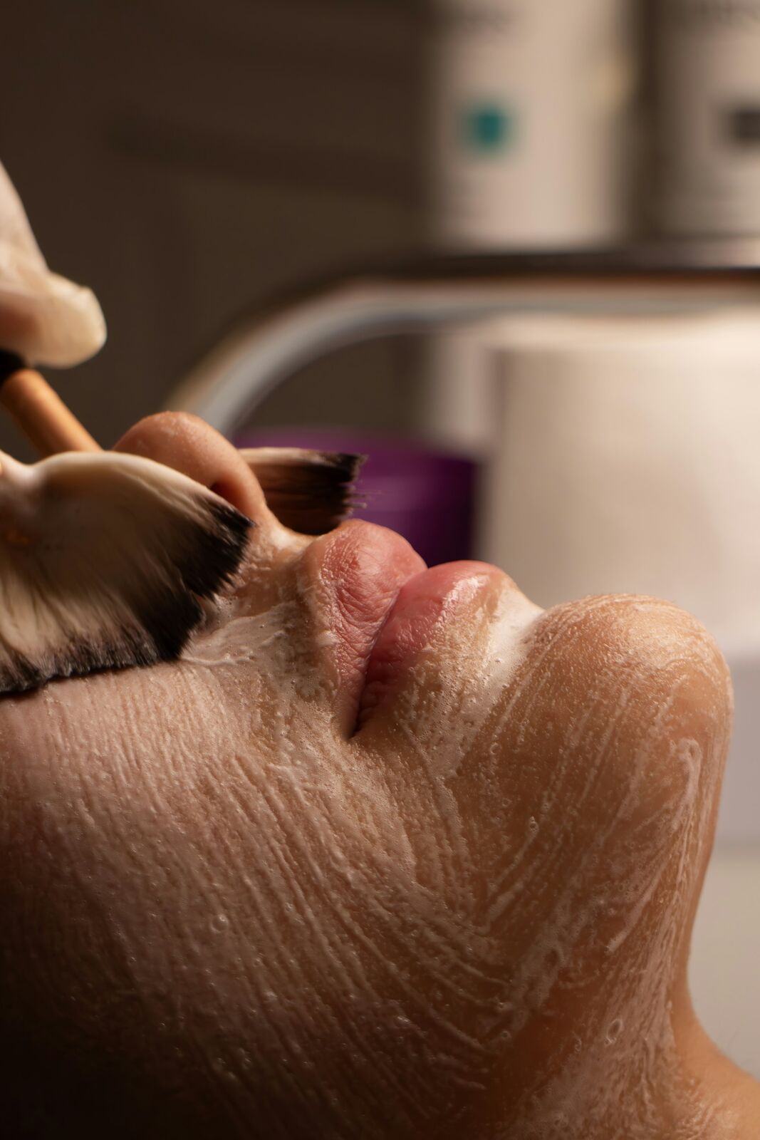 A facial mask being brushed onto a relaxed face
